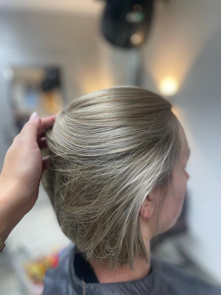 Stylist holding back a clients short blonde pixie haircut in a salon setting
