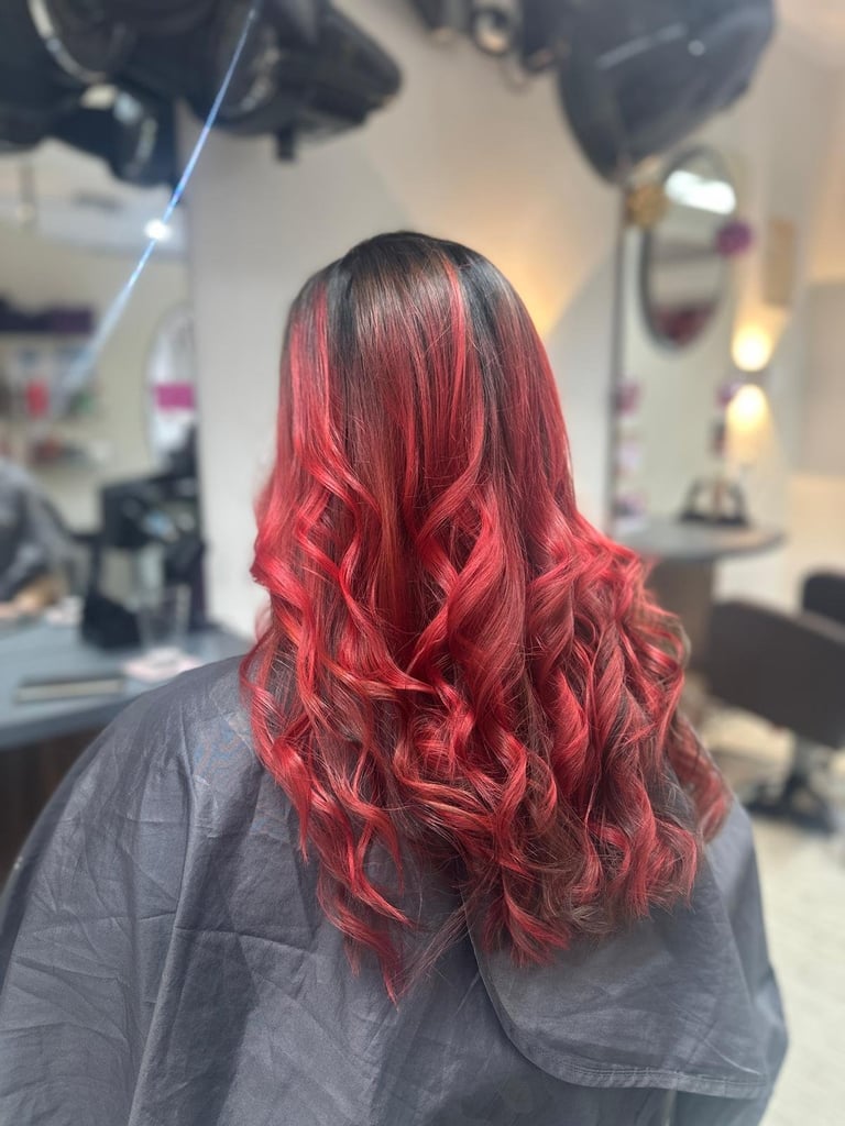 Person with long red wavy hair in a salon setting with professional lighting and mirrors visible in background